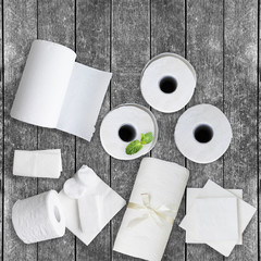 Paper tissue, white toilet  paper rolls, towels, napkins, cotton pads stacked on rustic wooden table. Copy space.