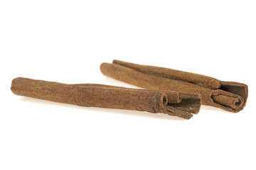 two cinnamon sticks on a white background