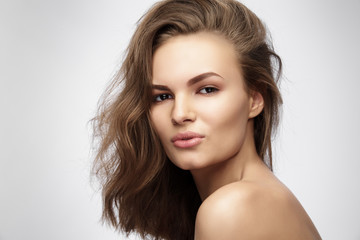 Fototapeta premium Beautiful young woman with long brown hair on gray background.