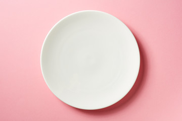White plate on pink background, from above