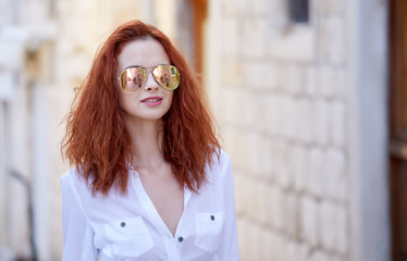 Portrait of happy smiling woman standing on the square on sunny summer or spring day outside, cute smiling woman looking at you, attractive young girl enjoying summer, filtered image, flare sunshine