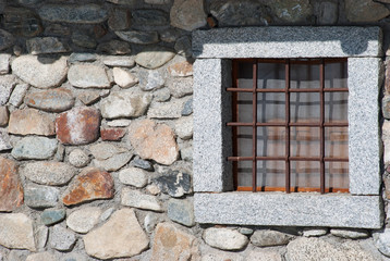 One stone window of a chalet with metal square grates