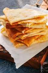 Close up of delicious crepes (blinis)  on a wooden board on a blue stone background.