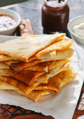Close up of delicious crepes (blinis)  on a wooden board on a blue stone background.