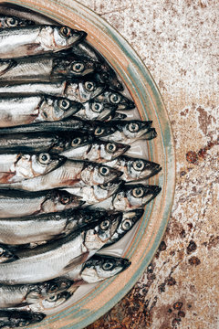 Cropped image of pile of fish on plate on rustic surface