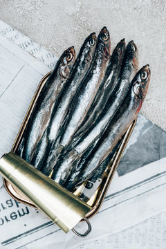 Top view of pile of fish in can on newspaper