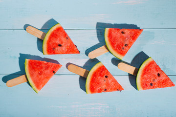 Slices of watermelon on blue wooden desk.