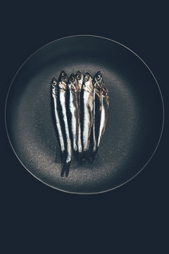 Top view of pile of fish in frying pan isolated on black