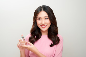 Beautiful asian woman holding a perfume bottle and applying it