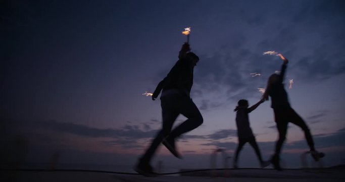 Partying teens enjoying their time together with fireworks after sunset