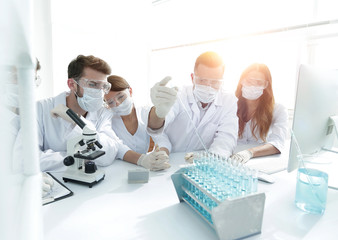 medical doctors are working with test tubes and microscope at th