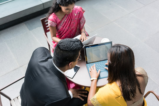 Three Indian Business People With Worried Facial Expression Talking During Break At Work