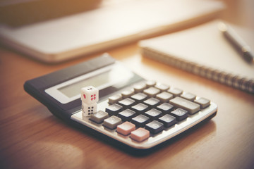 tax text on dice with blurred calculator on wooden table. abstract background to tax concept.