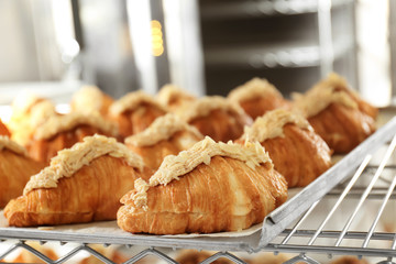 Shelf with delicious sweet croissants on tray in bakery