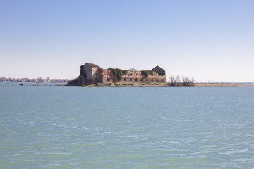 Naklejka premium small island with old abandoned decrepit orange brick house in the lagoon of Venice near Burano, Italy