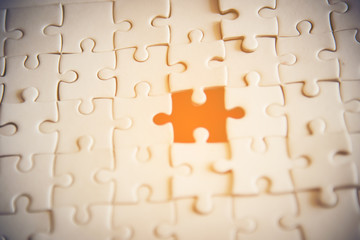 Fototapeta premium Jigsaw with one piece missing revealing orange background