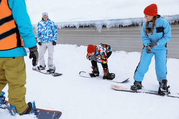 Young woman taking snowboard lessons at snowy resort. Winter vacation