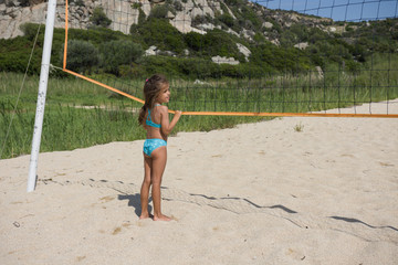Little cute girl holding in her hands volleyball net. Beach volleyball in the summer