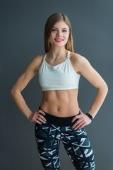 Beautiful athletic girl wearing sportswear in the background of a gray wall