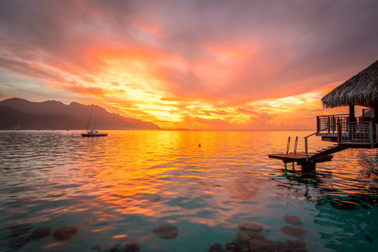 Fototapeta Romantic colorful sunset on a tropical island. Stunning view from overwater bungalow.