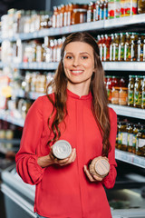 portrait of smiling woman with products in hands in hypermarket