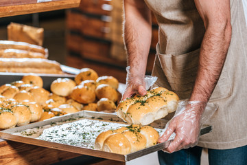 cropped shot of male shop assistant arranging pastry in supermarket