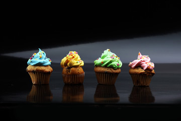 Tasty cupcakes on dark background. Birthday cupcake in rainbow colors.