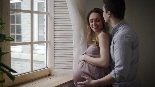 Parents to be are having good time next to the window