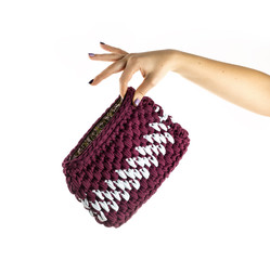 Women's hand is holding handmade crocheted and zipped clutch isolated on white background. Close up. © bint87