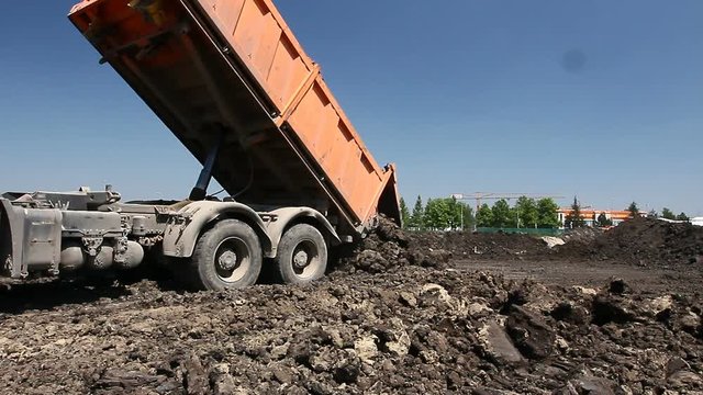 Many dump trucks are unloading soil at the same pile.
Dumper trucks are unloading soil or sand at construction site.
