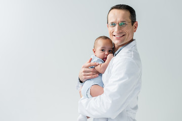 happy adult pediatrician holding little baby isolated on white - obrazy, fototapety, plakaty