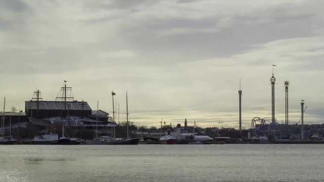 Timelapse of the ferryboats of Stockholm, Sweden, passing back and forth - with the amusement park Grona Lund - Gr&ouml;na Lund, the vasa ship / museum and other building along the coastline.