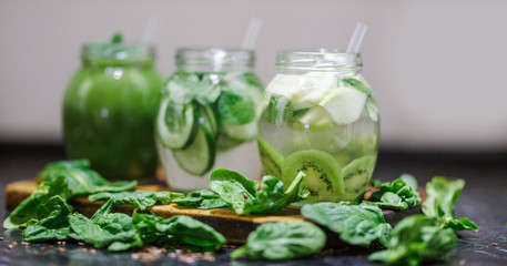 Blended green smoothie and infused detox water with cucumber, mint, kiwi spinach and apple for diet healthy eating and weight loss with space for a text. Grey backfround