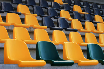 Rows of old plastic black and yellow seats at a stadium
