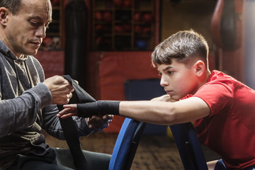 Male trainer straps the hands of a boxer before training for a fight