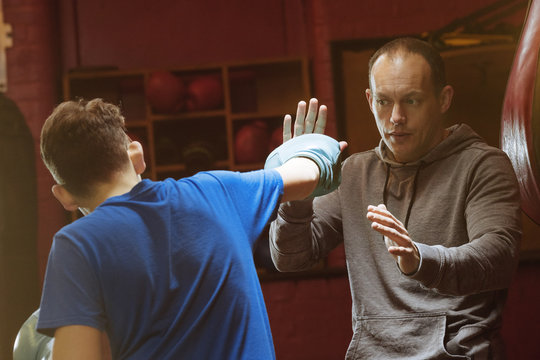 A young male boxers trains with his coach for a fight in the gym