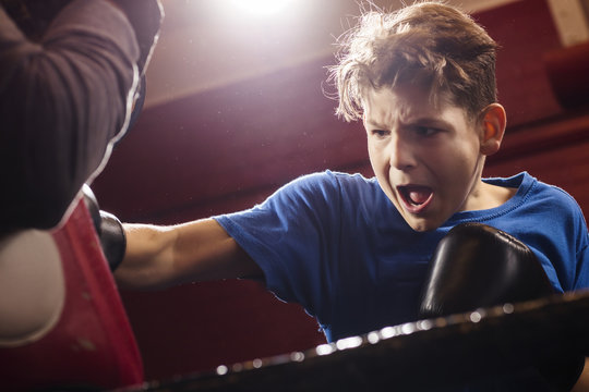 A young make boxer launching forwards while training for a fight in the ring