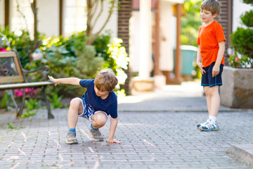 Two little school and preschool kids boys playing hopscotch on playground