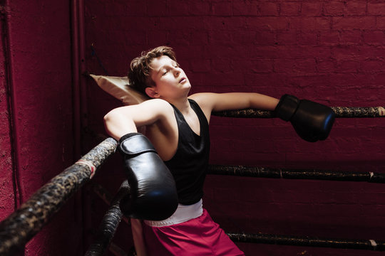 Young boxer taking a break on the ring during training to get his breath back