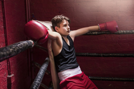Young boxer taking a break on the ring during training to get his breath back