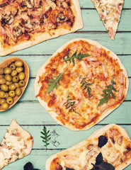 Different kinds of small pizza on rustic wooden background. Various homemade pizza, dinner party at home, top view.