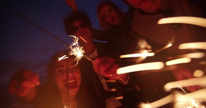 Young hipster friends having a party with fireworks at night