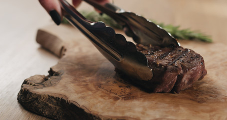 slicing medium rare fillet mignon steak on wood board
