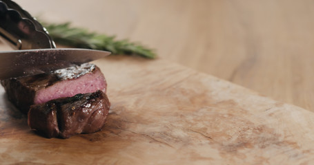 slicing medium fillet mignon steak on wood board