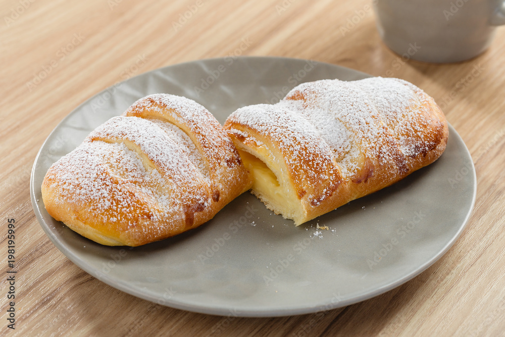 Sticker fresh baked puff bun with custard on gray plate