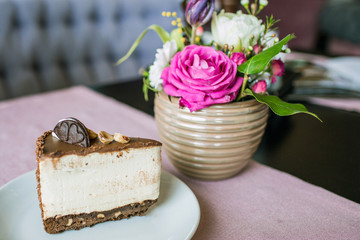 Creamy cheesecake with chocolate cookies and cream biscuits. Oreo cake and a beautiful vase with flowers on the table. A beautiful bouquet of flowers from roses and tulips.