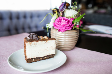 Creamy cheesecake with chocolate cookies and cream biscuits. Oreo cake and a beautiful vase with flowers on the table. A beautiful bouquet of flowers from roses and tulips.