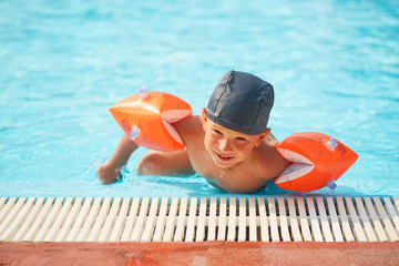 child in armlets for swimming in an outdoor pool with a water slide.