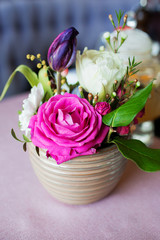 Pink flowers in a vase. A beautiful bouquet in a beige vase on the table. Beautiful design of the table in the cafe-restaurant.
