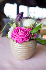 Pink flowers in a vase. A beautiful bouquet in a beige vase on the table. Beautiful design of the table in the cafe-restaurant.